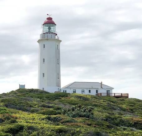 The white tower of the Danger Point Lighthouse against a blue sky