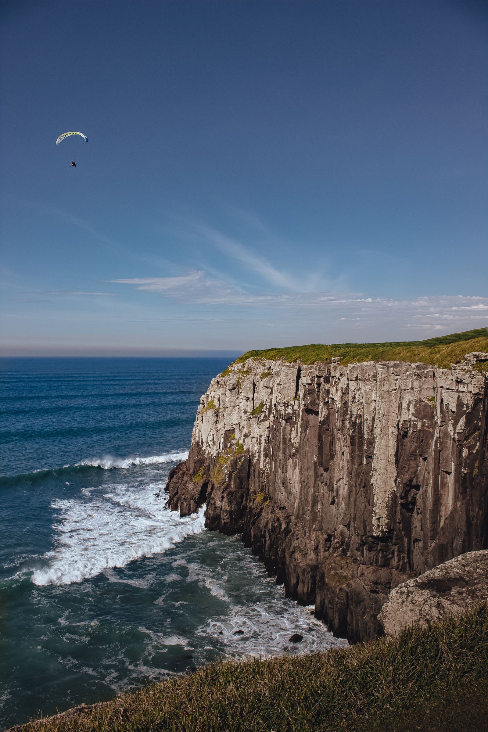 A paraglider soaring over the Hermanus cliffs above Walker Bay